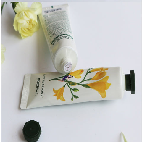 non greasy hand cream in floral packaging with a black cap and white tube on a light background with flowers.
