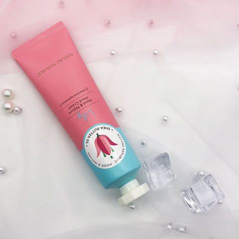 Non greasy hand cream in a pink and blue tube, surrounded by ice cubes and decorative pearls.